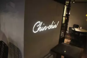 Объёмная надпись Chin-chin! встроена заподлицо в стену и подсвечена белым светом.